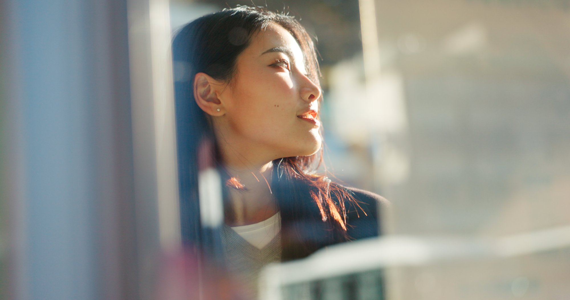 A woman gazing out a sunlit window, deep in thought